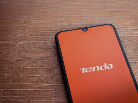 Lod, Israel - July 16,2023: Tenda Wifi app launch screen on smartphone on wooden background. Top view flat lay with copy space.