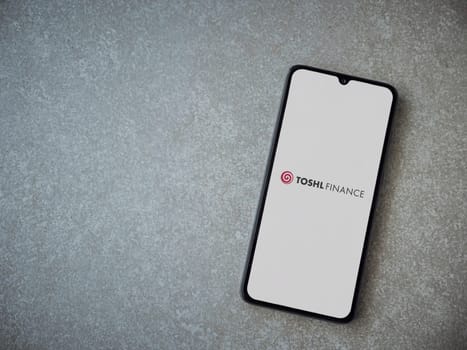 Lod, Israel - July 16,2023: Toshl Finance app launch screen on smartphone on ceramic stone background. Top view flat lay with copy space.