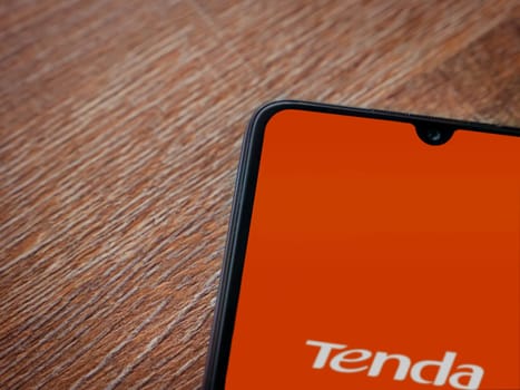Lod, Israel - July 16,2023: Tenda Wifi app launch screen on smartphone on wooden background. Top view flat lay with copy space.