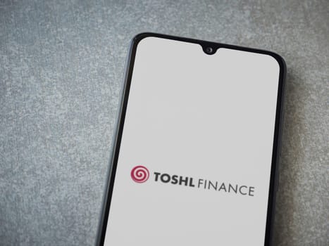 Lod, Israel - July 16,2023: Toshl Finance app launch screen on smartphone on ceramic stone background. Top view flat lay with copy space.