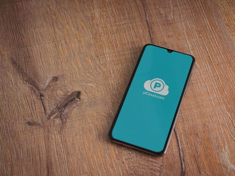 Lod, Israel - July 16,2023: pCloud app launch screen on smartphone on wooden background. Top view flat lay with copy space.