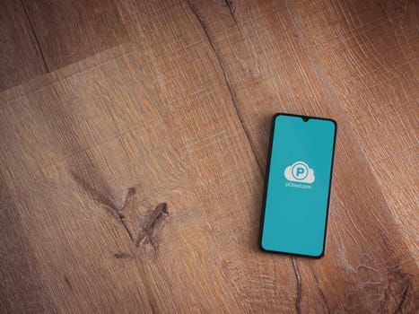 Lod, Israel - July 16,2023: pCloud app launch screen on smartphone on wooden background. Top view flat lay with copy space.