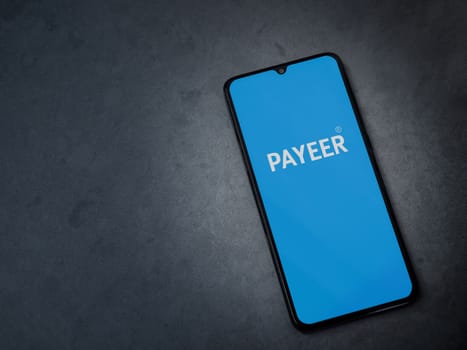 Lod, Israel - July 16,2023: PAYEER app launch screen on smartphone on dark marble stone background. Top view flat lay with copy space.