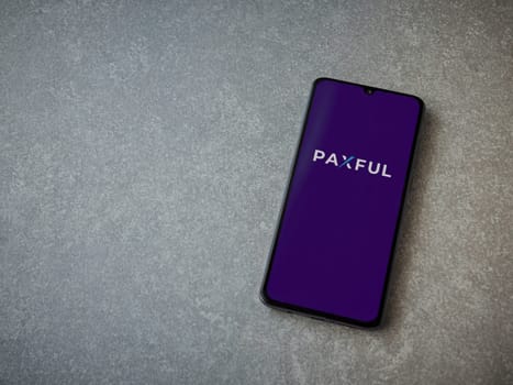 Lod, Israel - July 16,2023: Paxful app launch screen on smartphone on ceramic stone background. Top view flat lay with copy space.