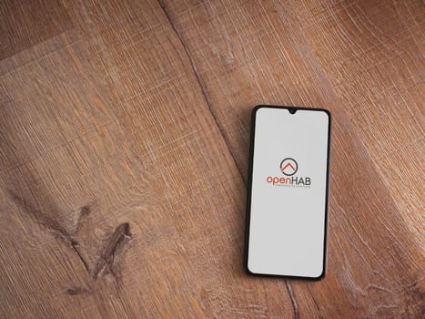 Lod, Israel - July 16,2023: openHAB app launch screen on smartphone on wooden background. Top view flat lay with copy space.