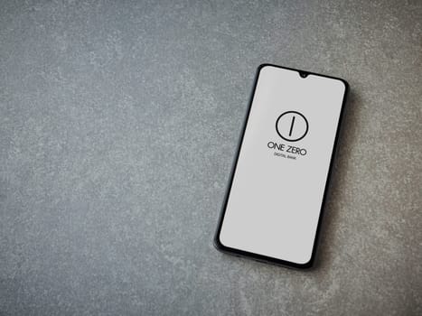 Lod, Israel - July 16,2023: One Zero app launch screen on smartphone on ceramic stone background. Top view flat lay with copy space.