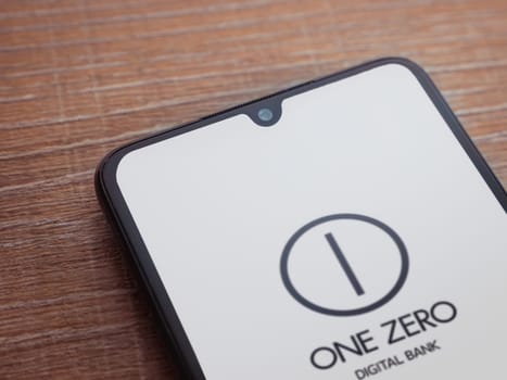 Lod, Israel - July 16,2023: One Zero app launch screen on smartphone on wooden background. Top view flat lay with copy space.