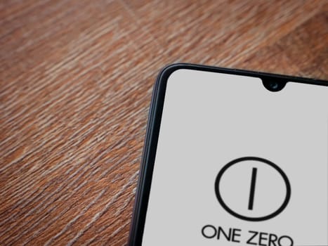 Lod, Israel - July 16,2023: One Zero app launch screen on smartphone on wooden background. Top view flat lay with copy space.