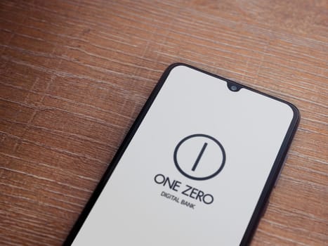 Lod, Israel - July 16,2023: One Zero app launch screen on smartphone on wooden background. Top view flat lay with copy space.