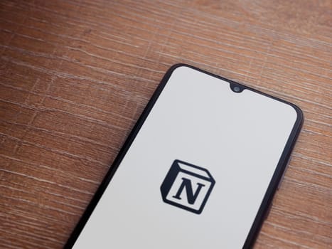 Lod, Israel - July 16,2023: Notion app launch screen on smartphone on wooden background. Top view flat lay with copy space.