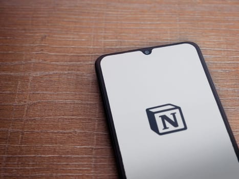 Lod, Israel - July 16,2023: Notion app launch screen on smartphone on wooden background. Top view flat lay with copy space.