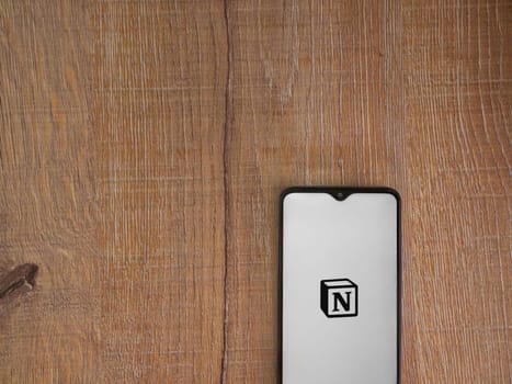 Lod, Israel - July 16,2023: Notion app launch screen on smartphone on wooden background. Top view flat lay with copy space.