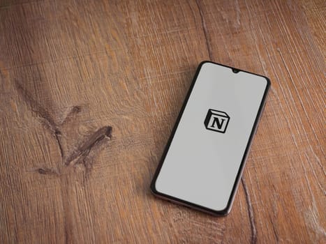 Lod, Israel - July 16,2023: Notion app launch screen on smartphone on wooden background. Top view flat lay with copy space.