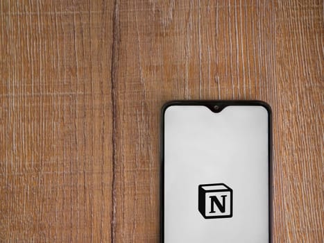 Lod, Israel - July 16,2023: Notion app launch screen on smartphone on wooden background. Top view flat lay with copy space.