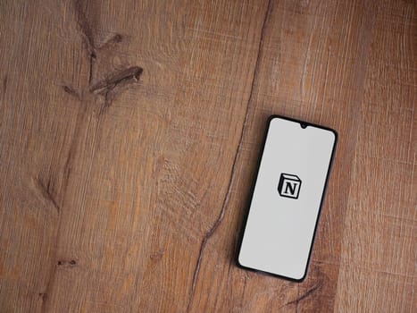 Lod, Israel - July 16,2023: Notion app launch screen on smartphone on wooden background. Top view flat lay with copy space.