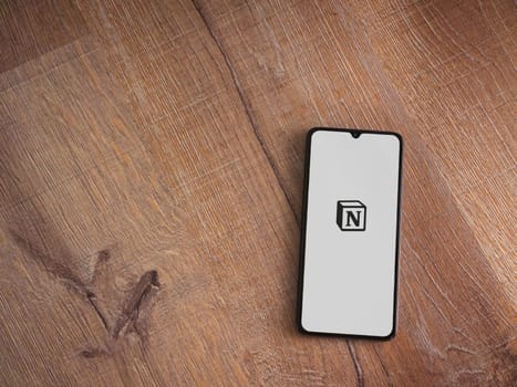 Lod, Israel - July 16,2023: Notion app launch screen on smartphone on wooden background. Top view flat lay with copy space.