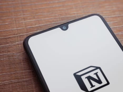 Lod, Israel - July 16,2023: Notion app launch screen on smartphone on wooden background. Top view flat lay with copy space.