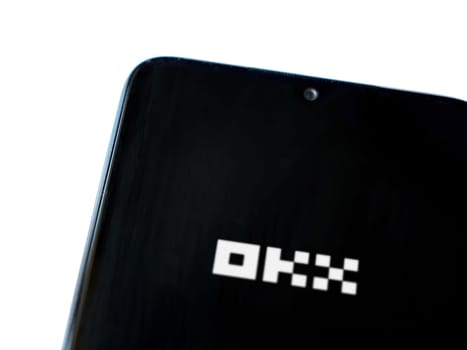 Lod, Israel - July 16,2023: OKX app launch screen on smartphone on white background. Top view flat lay with copy space.