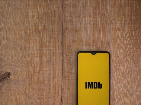Lod, Israel - July 16,2023: IDMb app launch screen on smartphone on wooden background. Top view flat lay with copy space.