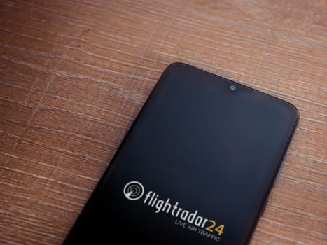 Lod, Israel - July 16,2023: Flightradar24 Flight Tracker app launch screen on smartphone on wooden background. Top view flat lay with copy space.