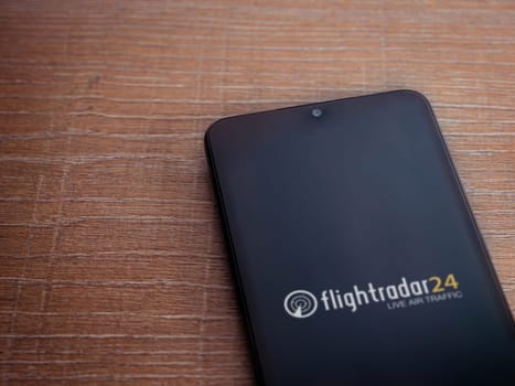 Lod, Israel - July 16,2023: Flightradar24 Flight Tracker app launch screen on smartphone on wooden background. Top view flat lay with copy space.
