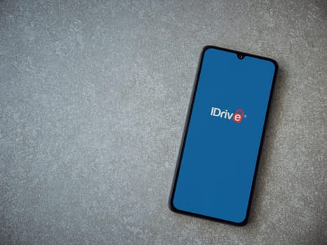Lod, Israel - July 16,2023: IDrive Online Backup app launch screen on smartphone on ceramic stone background. Top view flat lay with copy space.