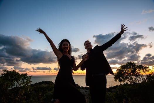 Happy young couple backlit against sunset background