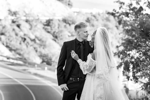 Happy newlyweds kiss against the backdrop of a beautiful mountain landscape, the girl and the guy look at each other passionately