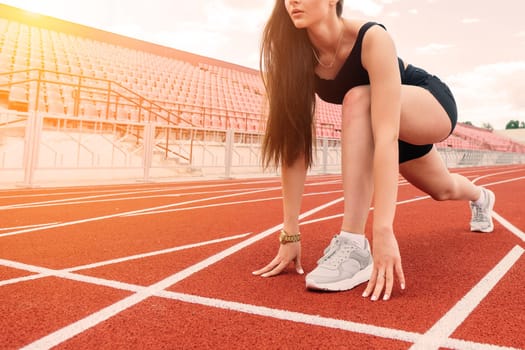 Young, beautiful girl athlete in sportswear is training and running, stretching at the stadium