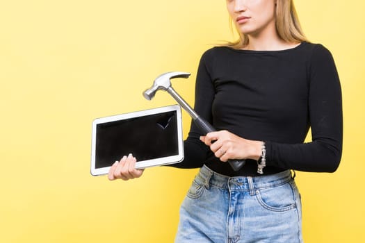 Laptop Repair. Female with hammer and laptop on a yellow background