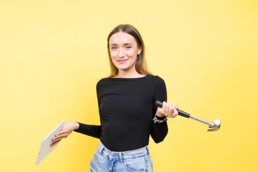 Woman with tablet and a hammer, Studio lighting yellow background isolated, copy space