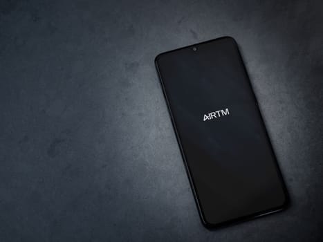 Lod, Israel - July 16,2023: AirTM app launch screen on smartphone on dark marble stone background. Top view flat lay with copy space.