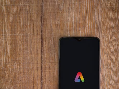 Lod, Israel - July 16,2023: Adobe Express - Graphic Design app launch screen on smartphone on wooden background.. Top view flat lay with copy space.