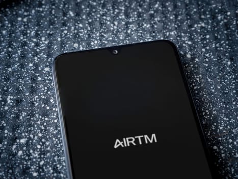 Lod, Israel - July 16,2023: AirTM app launch screen on smartphone on metallic background. Close up top view flat lay.
