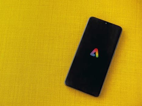 Lod, Israel - July 16,2023: Adobe Express - Graphic Design app launch screen on smartphone on yellow fabric background. Top view flat lay with copy space.