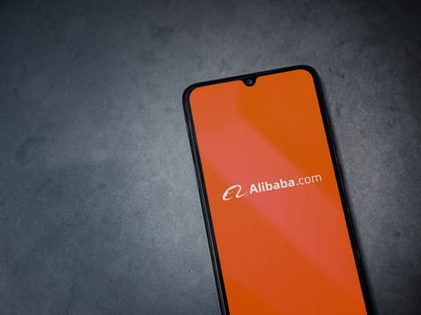 Lod, Israel - July 16,2023: Alibaba.com app launch screen on smartphone on dark marble stone background. Top view flat lay with copy space.