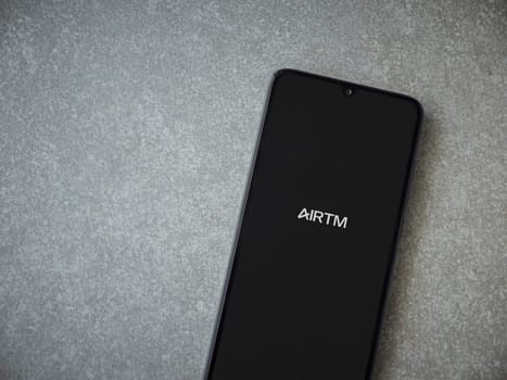 Lod, Israel - July 16,2023: AirTM app launch screen on smartphone on ceramic stone background. Top view flat lay with copy space.