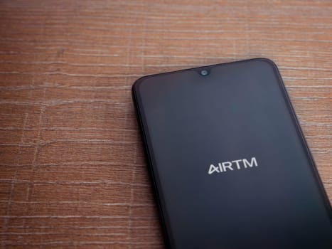 Lod, Israel - July 16,2023: AirTM app launch screen on smartphone on wooden background. Top view flat lay with copy space.