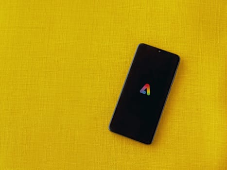 Lod, Israel - July 16,2023: Adobe Express - Graphic Design app launch screen on smartphone on yellow fabric background.. Top view flat lay with copy space.