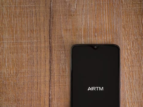 Lod, Israel - July 16,2023: AirTM app launch screen on smartphone on wooden background. Top view flat lay with copy space.