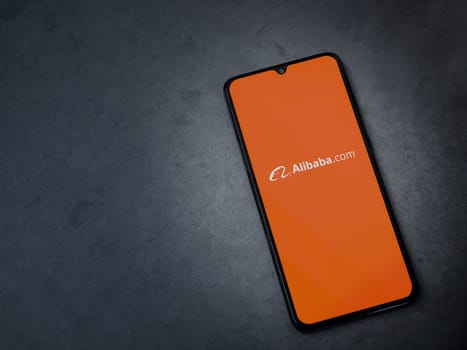 Lod, Israel - July 16,2023: Alibaba.com app launch screen on smartphone on dark marble stone background. Top view flat lay with copy space.