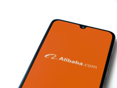 Lod, Israel - July 16,2023: Alibaba.com app launch screen on smartphone on white background. Top view flat lay with copy space.