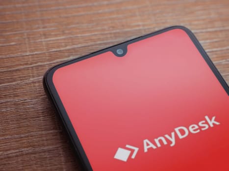Lod, Israel - July 16,2023: Anydesk app launch screen on smartphone on wooden background. Top view flat lay with copy space.