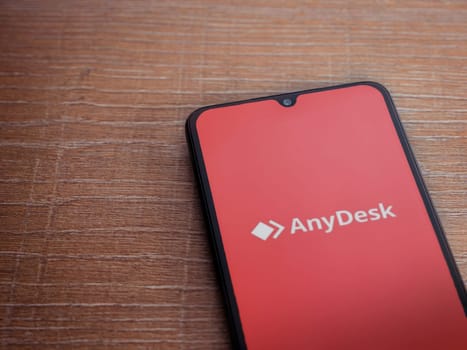 Lod, Israel - July 16,2023: Anydesk app launch screen on smartphone on wooden background. Top view flat lay with copy space.
