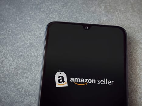 Lod, Israel - July 16,2023: Amazon Seller app launch screen on smartphone on ceramic stone background. Top view flat lay with copy space.