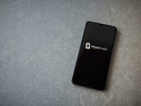Lod, Israel - July 16,2023: Amazon Seller app launch screen on smartphone on ceramic stone background. Top view flat lay with copy space.