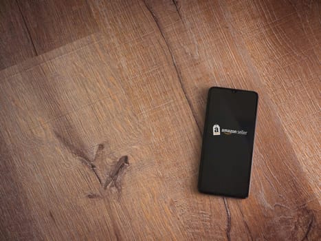 Lod, Israel - July 16,2023: Amazon Seller app launch screen on smartphone on wooden background. Top view flat lay with copy space.