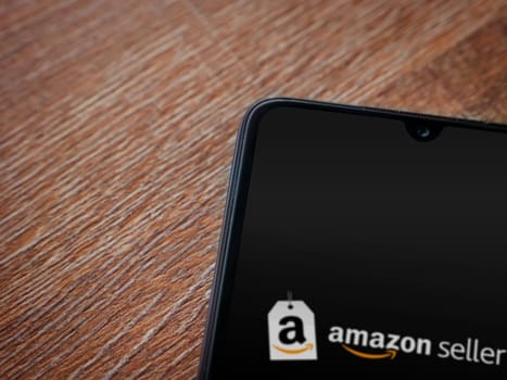 Lod, Israel - July 16,2023: Amazon Seller app launch screen on smartphone on wooden background. Top view flat lay with copy space.