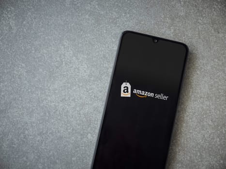 Lod, Israel - July 16,2023: Amazon Seller app launch screen on smartphone on ceramic stone background. Top view flat lay with copy space.