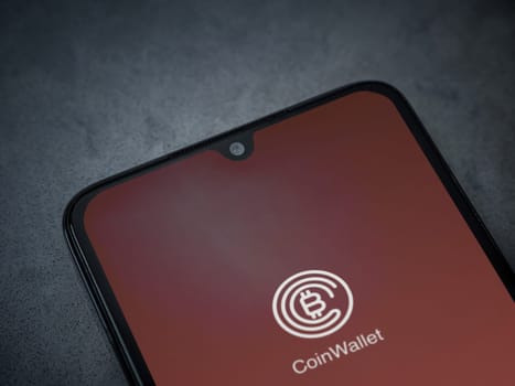 Lod, Israel - July 16,2023: CoinWallet app launch screen on smartphone on dark marble stone background. Top view flat lay with copy space.